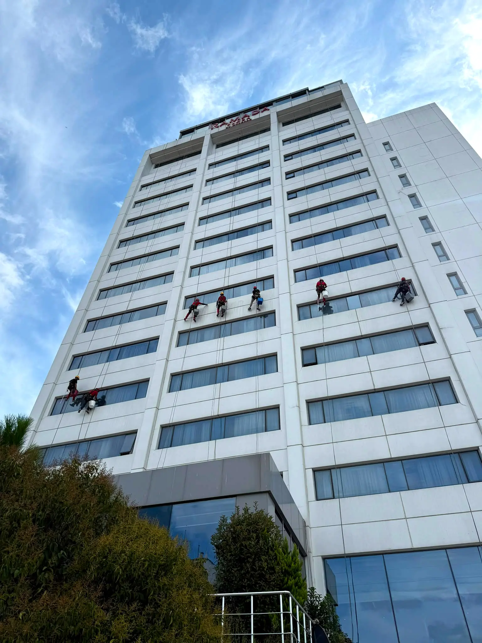 Ramada Plaza İstanbul’da beyaz otel cephesinde iple erişimle cam temizliği yapan yaklaşık 8 kişilik ekip